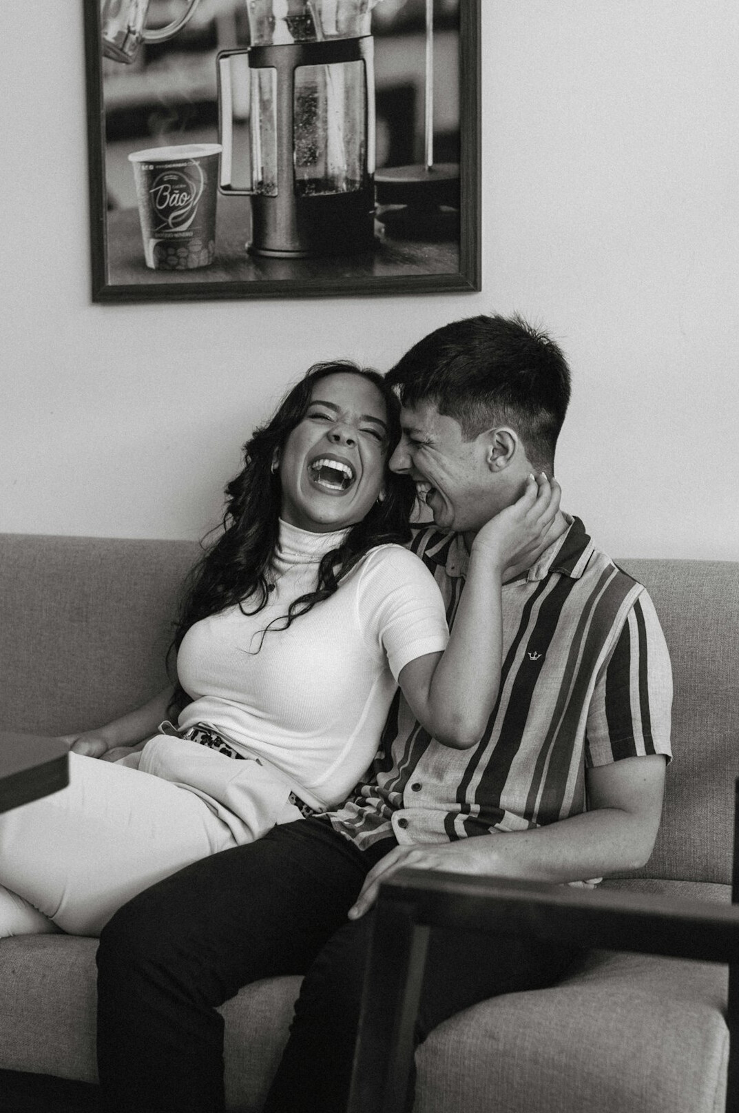 Two colleagues laughing together while looking at a laptop